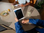Hand houdt tablet beet op bruine eettafel