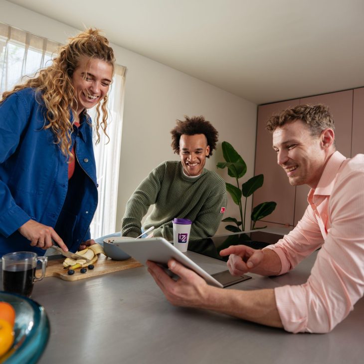 Vrouw en 2 mannen kijken en lachen naar tablet