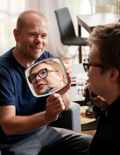 zorgmedewerker houdt spiegel omhoog voor client die zich scheert