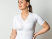 Vrouw kijkt naar links heeft een wit houdingshirt aan. En heeft haar linkerarm in haar zij.