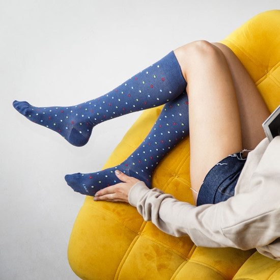 Een persoon zit op een gele fauteuil met hoge donker blauwe sokken met een bovenaanzicht.