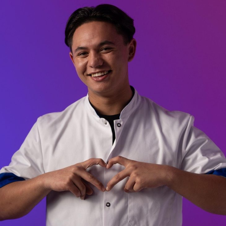 Jonge mannelijke zorgmedewerker vormt een hart met zijn wijsvinger en middelvinger